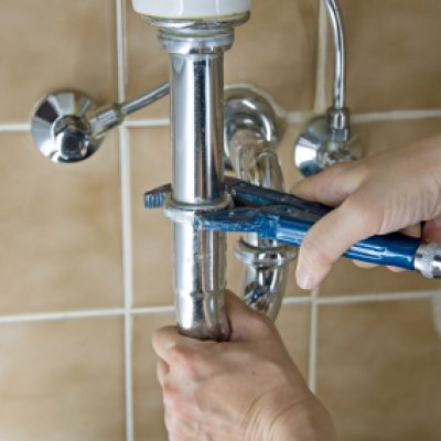 hands of a plumber fixing a leaking tap